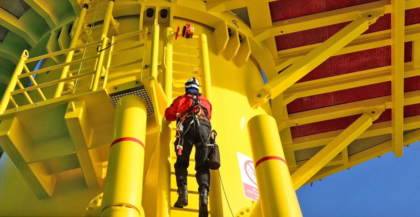 Workman climbing up ladder on wind turbine